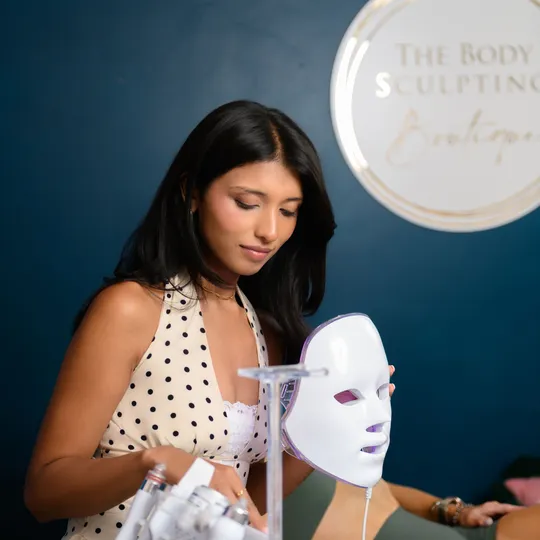 Boutique practitioner presenting an LED light therapy mask